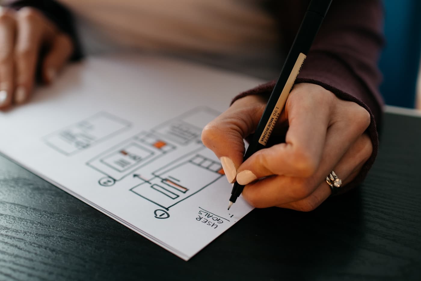 Someone sketching a page layout onto paper with a pen