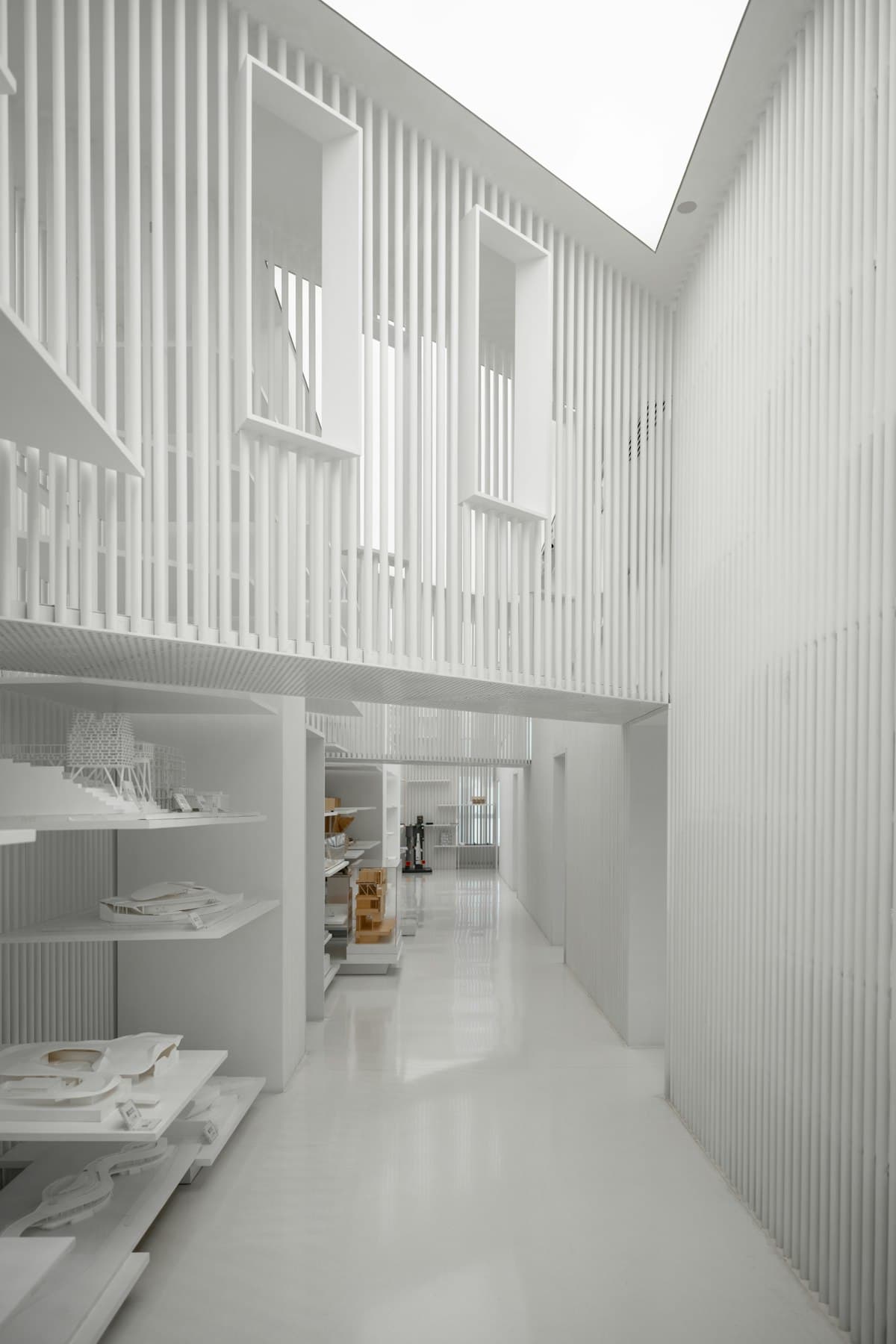 A white, top-lit corridor lined with slatted panels