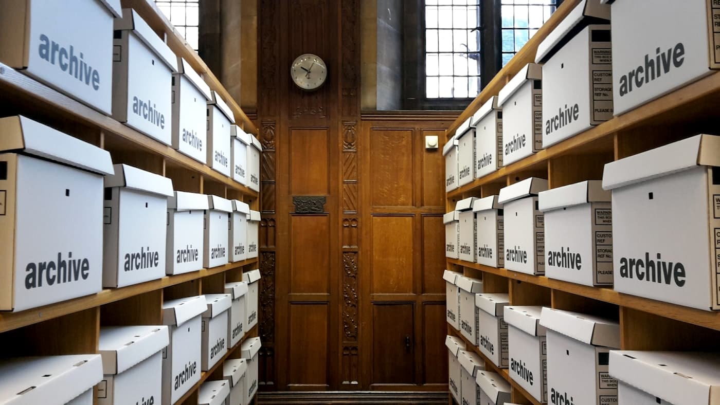 Shelves of white archive boxes lining a corridor