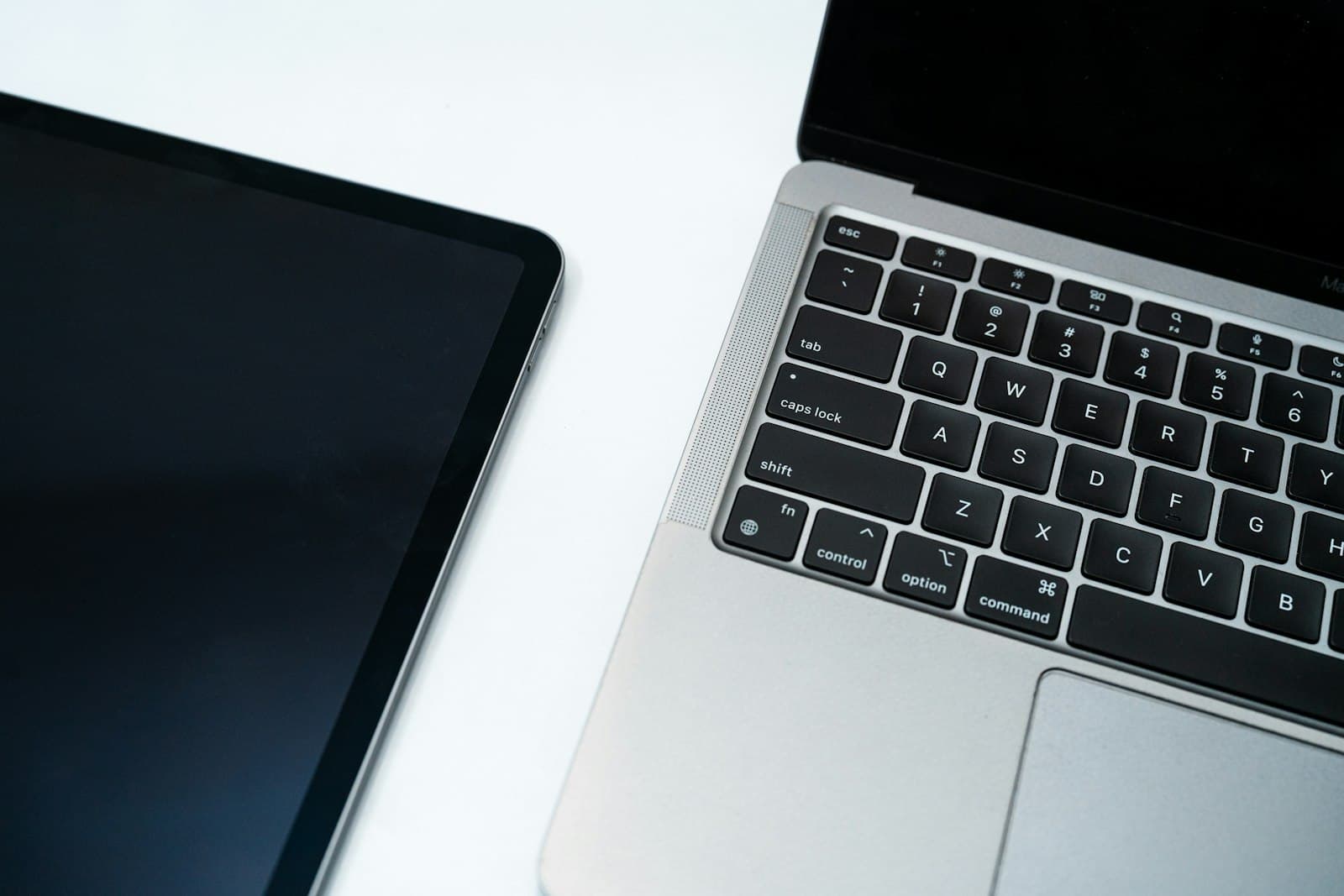 A laptop and tablet arranged on a plain white surface