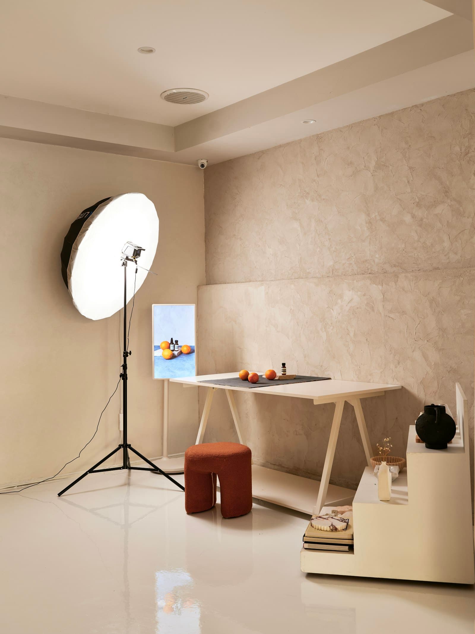 A small photography studio with a softbox light, a table and a screen